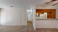 Located at 4501 Summerhill Rd in Texarkana, TX, this single-floor residence offers a functional and comfortable layout across two bedrooms and two bathrooms. The combined living and dining area is carpeted throughout, with a ceiling fan overhead and a glass patio door that invites natural light and outdoor access. The kitchen is positioned adjacent to the living area behind a half-wall pass-through counter, featuring warm wood cabinetry, a light-toned countertop, and white appliances including a refrigerator, stove, and microwave. A hallway connects the living spaces to the private quarters, maintaining a clear and efficient flow throughout. The primary bedroom is a well-proportioned retreat with a ceiling fan, a wide bay-style window for natural light, and access to a walk-in closet equipped with built-in shelving and a hanging rod. The second bedroom also features a ceiling fan and a window, offering a comfortable and functional space. Both bathrooms are well-appointed, with one featuring a wood-toned vanity, granite-style countertop, and a tiled tub-shower combination. Textured ceilings are consistent throughout the home, contributing to the overall character of the space.