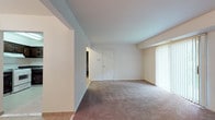 Located at 1600 Laurel Rd in Lindenwold, NJ, this single-floor unit offers a practical and comfortable layout across several well-defined living spaces. The living room is generously sized, featuring neutral-toned wall-to-wall carpeting, clean white walls, and a large sliding glass door dressed with vertical blinds that floods the space with natural light and provides access to outdoor greenery views. An additional window in the secondary carpeted room further enhances the natural light throughout.

The kitchen is equipped with dark-stained cabinetry featuring raised-panel doors, dark granite-style countertops, and white appliances including a gas range, dishwasher, and refrigerator. Light tile flooring runs throughout the kitchen and entry areas, complementing the overall neutral palette. A hallway connects the kitchen to the rest of the unit seamlessly.

The bedroom areas are carpeted and offer ample wall space, with closet access and connecting doors. The bathroom showcases a retro aesthetic with sky-blue wall tiles, a classic black-and-white mosaic tile floor, a white vanity with mirror, and a full tub-shower combination, creating a distinctly vintage yet functional feel throughout.