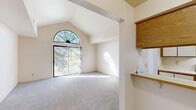 Located at 540 Hampton Ln NW in Walker, Michigan, this single-floor residence offers a well-organized layout with a bright, open feel throughout. The living area is among the most architecturally distinctive spaces in the unit, showcasing soaring vaulted ceilings with an exposed beam detail and a dramatic arched transom window positioned above a sliding glass door. This combination floods the room with natural light and provides views of the surrounding tree line, creating an airy and inviting atmosphere. The space is finished with neutral carpet and light-toned walls that complement the open design.

The galley-style kitchen is efficiently arranged with white cabinetry trimmed in warm oak accents, white appliances including a gas range and full-size refrigerator, a stainless steel sink, and tile flooring. Upper and lower cabinets line both walls, maximizing storage and counter space throughout the corridor layout.

The bedroom areas are carpeted and neutrally finished, each offering a calm, functional environment. One bedroom features a wide closet with louvered bi-fold doors and a generous hanging rod, providing practical storage. Additional rooms benefit from standard windows that introduce natural light and outdoor views. Overall, the space presents a clean, functional, and light-filled environment suitable for comfortable everyday living.