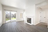 This thoughtfully designed 2-bedroom, 2-bathroom single-floor residence offers a cohesive, modern aesthetic across every room. Light gray wood-look flooring runs throughout the entire space, complemented by neutral wall tones that create a bright and airy atmosphere.

The living room serves as the heart of the home, featuring a tile-surround fireplace and a sliding glass door that opens to an outdoor patio, filling the room with natural light and providing views of the surrounding greenery.

The kitchen is efficiently laid out with white shaker cabinets, a speckled quartz countertop, subway tile backsplash, stainless steel appliances including a refrigerator, electric range, and built-in microwave, plus a single-basin sink with a matte black faucet.

The primary bedroom offers a comfortable footprint with a large window framing outdoor tree views and access to a walk-in closet with wire shelving. The second bedroom is equally bright, featuring its own window with natural views.

Both bathrooms maintain a clean, minimalist design. One includes a full tub/shower combo with matte black hardware. A connecting hallway ties the layout together efficiently. Throughout, the space benefits from abundant natural light, consistent finishes, and a well-organized floor plan.