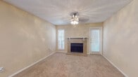This single-story space is designed with a practical and comfortable layout. The living room serves as the focal point, featuring a wood-burning fireplace with a tile surround and white mantel, complemented by soft carpeting and a ceiling fan with a light fixture overhead. Natural light filters in through blindblinds-covered windows, creating a warm, neutral ambiance throughout. A dedicated entryway with wood-style flooring transitions smoothly into the carpeted living area.

The kitchen is equipped with black appliances, including an electric range and a full-size refrigerator, alongside white cabinetry and speckled countertops. Wood-style flooring runs through the kitchen, adding a practical, easy-to-clean surface.

The bedrooms continue the neutral palette with beige walls, plush carpeting, ceiling fans with light fixtures, and windows with blinds providing natural light. One additional room features built-in corner shelving and a utility sink, offering versatile functionality as an office or flex space.

The bathroom includes a full tub-shower combo with white tile surround, wood-style flooring, white cabinetry, a speckled countertop vanity, and a large mirror with overhead lighting, completing this well-rounded space.