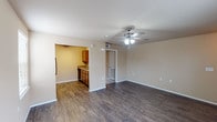 This single-floor residence offers a practical and comfortable layout designed for easy everyday living. The main living area features dark hardwood-style flooring, neutral beige walls, and a ceiling fan with integrated lighting, creating a bright and airy atmosphere. A window allows natural light to fill the space, and the open sightline into the kitchen makes the area feel connected and welcoming.

The kitchen is well-appointed with warm wood cabinetry, laminate countertops, a double-basin sink, and black appliances including a refrigerator, electric range, and dishwasher. The hardwood-style flooring continues seamlessly throughout the kitchen.

The two bedrooms are generously sized, each featuring plush carpeting, ceiling fans with lighting, and ample wall space. Natural light filters through windows fitted with blinds, and each room provides access to adjacent spaces such as closets or hallways.

The bathroom is neatly laid out with a wood vanity, stone-pattern countertop, a full tub-shower combination, and durable hardwood-style flooring. A dedicated in-unit laundry area houses a full-size washer and dryer with overhead wire shelving for additional storage. Clean white trim and consistent neutral tones throughout the home create a cohesive, move-in ready environment.