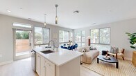 Located on Spring Street in Silver Spring, MD, this modern 1-bedroom, 2-bathroom residence offers a thoughtfully designed open-concept layout with stylish, contemporary finishes. The heart of the home is a bright, seamlessly connected kitchen, dining, and living area bathed in natural light from expansive floor-to-ceiling windows that frame lush green views. The kitchen is outfitted with crisp white shaker cabinetry, a white subway tile backsplash, stainless steel appliances, and a large quartz-topped island with an undermount sink and pendant lighting above. Light hardwood flooring runs throughout, enhancing the airy feel of the space. The dining area transitions smoothly into the living room, which features a generous window wall overlooking the surrounding greenery. The bedroom is a serene retreat, highlighted by a dramatic textured accent wall, large windows with outdoor views, and two closets for ample storage. The bathrooms offer clean, modern finishes, including marble-look tile flooring and a subway-tiled tub-shower combination. A corner nook with wraparound windows provides an ideal spot for a home office or reading area, taking full advantage of the natural light and neighborhood views.