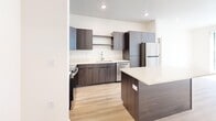 Located at 868 25th St in Ogden, Utah, this modern 2-bedroom, 2-bathroom unit offers a well-designed single-floor layout with contemporary finishes throughout. The open-concept living area seamlessly connects the kitchen, dining, and living spaces, creating a bright and functional flow. The kitchen is a standout feature, equipped with dark wood-tone cabinetry, a large center island with a white quartz-style countertop, stainless steel appliances including a refrigerator, microwave, and range, and recessed lighting overhead. Light wood-style flooring runs throughout the entire unit, contributing to a clean and cohesive aesthetic. The spacious primary bedroom includes a ceiling fan and direct access to a full bathroom featuring a soaking tub/shower combo and a walk-in closet with built-in shelving. The second bedroom is well-proportioned and benefits from natural light through large windows with views of surrounding greenery. A second bathroom offers a dark-toned vanity with an undermount sink and a large mirror. Additional conveniences include in-unit laundry and two closets for ample storage. The unit's neutral color palette and modern design elements create a clean, contemporary living environment.