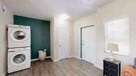 This efficiently laid-out 1-bedroom, 1-bathroom unit offers a thoughtful design with a cohesive aesthetic carried throughout by a bold teal accent wall that adds character to each room. Light wood-look flooring flows seamlessly across the entire space, complementing the neutral cream-toned walls.

The kitchen is a standout feature, offering rich dark-wood cabinetry, light stone countertops, and a full suite of stainless steel appliances including a refrigerator, range, over-the-range microwave, and dishwasher. Multiple windows flood the kitchen and adjoining dining area with natural light, creating a bright and functional space. A stacked washer and dryer unit is conveniently integrated into the layout.

The combined living room and dining area provides a comfortable, open feel, with windows dressed in white blinds that allow ample natural light. The space transitions smoothly into the bedroom, which features a striking teal accent wall, dual sliding wood-panel closets offering generous storage, and a full-length mirror. The bathroom continues the teal accent theme and includes a shower, vanity with dark cabinetry, and wood-look flooring. The entryway is welcoming, with clean lines and practical layout making efficient use of every square foot.