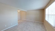 This single-story home offers three bedrooms and two full bathrooms within a well-organized layout finished in a consistent, neutral palette. Light beige walls and large-format tile flooring run throughout the living areas and bedrooms, creating a cohesive and easy-to-maintain interior. Textured ceilings are present in most rooms, adding subtle dimension overhead.

The main living area connects openly to a secondary space, both finished with the same tile flooring and warmed by natural-toned walls. Ceiling fans with light fixtures are installed in the living areas and bedrooms, contributing to both comfort and ambient lighting.

The bedrooms are generously proportioned, with windows providing natural light and views to the outdoors. One bedroom features a built-in shelving unit alongside a standard closet door, offering additional storage. Another bedroom benefits from dual windows.

The kitchen includes granite-look laminate countertops, a double stainless steel sink, white shaker-style cabinetry, and a black dishwasher. Both bathrooms are finished in white, each featuring a tub-shower combination, a vanity with a large mirror, and tile flooring. A dedicated utility room houses the water heater and includes washer/dryer hookups with wire shelving.