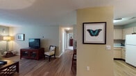 Located at 2000 Trellis Point in Holly Springs, NC, this single-floor residence offers a well-designed layout that balances comfort and functionality throughout. The living room serves as the heart of the home, featuring warm hardwood-style flooring, neutral-toned walls, and generous natural light streaming through large windows dressed with elegant draping curtains. The open and airy feel is enhanced by a textured ceiling and tasteful décor.

The kitchen is equipped with ample light wood cabinetry, generous counter space, a double-basin sink, and white appliances including a range and over-the-range microwave — all laid out for efficient use. Adjacent to the kitchen, the dining area features hardwood-style flooring and is centered beneath a classic chandelier, creating an inviting space for meals.

Each bedroom is carpeted and bright, with ceiling fans, natural light from well-positioned windows, and warm, neutral wall tones. The bathrooms are clean and functional, with one featuring a full tub-shower combination and another with a wide vanity and convenient access to an in-unit laundry room complete with a washer and dryer. A connecting hallway ties the rooms together with a cohesive, comfortable flow throughout this well-maintained single-level home.