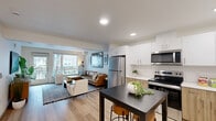 Located in Renton, WA, this Solera one-bedroom, one-bathroom residence offers a thoughtfully designed single-floor layout with contemporary finishes and a bright, cohesive aesthetic. The open-concept kitchen and living area serves as the heart of the home, featuring a modern kitchen outfitted with stainless steel appliances — including a refrigerator, electric range, microwave, and dishwasher — paired with two-tone cabinetry combining white upper cabinets and warm wood-toned lower cabinets, all set against clean white countertops. Light wood-style flooring flows throughout, enhancing the airy feel of the space. The living room benefits from natural light through large windows and a glass door that opens to a private balcony, offering outdoor views. The bedroom is a calm retreat, carpeted for comfort, with a window allowing in natural light and access to two closets for ample storage. The full bathroom features a wide vanity with white cabinetry, a large mirror, and a tub/shower combination, all finished with the same light wood flooring. Recessed lighting throughout the space adds a polished, modern touch to every room, making this a well-rounded and functional home.