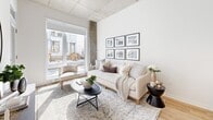 Located at 305 Rue Quinlan in Montréal, this thoughtfully designed one-bedroom, two-bathroom unit offers a clean, contemporary aesthetic across a single floor. Exposed concrete ceilings lend an industrial character throughout, while light hardwood flooring and crisp white walls create a bright, cohesive atmosphere.

The open-concept kitchen features two-tone cabinetry in natural wood and white, paired with quartz countertops, a tile backsplash, and stainless steel appliances including a built-in range and refrigerator. The kitchen flows seamlessly into the dining area, where large-format glazing allows natural light to fill the space. The living room benefits from floor-to-ceiling windows that invite in abundant daylight and provide views of the surrounding streetscape.

The bedroom is a serene retreat, complete with a full-height window, warm wood flooring, and a closet with tall-panel doors. Two well-appointed bathrooms serve the unit — one featuring a soaking tub with a glass enclosure and white tile surround, and the other finished with a floating oak vanity, integrated sink, and large mirror cabinet. The entryway is welcoming, accented by a glass-paneled door and generous ceiling height. Every detail reflects a modern, refined sensibility suited to urban living.