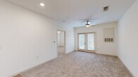 Located at 8240 Windsor Hill Blvd in North Charleston, SC, this 2-bedroom, 1-bathroom residence offers a thoughtfully designed single-floor layout with a clean, neutral aesthetic throughout. The open living room is bright and welcoming, featuring plush carpeting, a ceiling fan, and a set of French doors that invite natural light and provide outdoor access. The kitchen is well-appointed with crisp white shaker-style cabinetry, granite countertops, light hardwood-style flooring, and stainless steel appliances including a dishwasher and refrigerator. A hallway connects the living areas to the two bedrooms, lined with multiple paneled doors providing access to closets and the bathroom. The primary bedroom is generously proportioned, carpeted, and includes a ceiling fan and a window for natural light. A dedicated walk-in closet with wire shelving offers ample storage. The shared bathroom features a full soaking tub and shower combination with tiled surroundings and hardwood-style flooring. Throughout the residence, the light-toned walls, consistent flooring choices, and recessed lighting contribute to a clean, cohesive, and comfortable living environment.