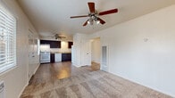 This 2-bedroom, 1-bathroom single-floor unit in Sacramento, CA offers a practical and comfortable layout across a well-utilized footprint. The open living and dining area features plush wall-to-wall carpeting, a ceiling fan with light fixture, a textured ceiling, and a louvered wall vent, creating a simple and functional common space. The kitchen flows directly off the living area and is equipped with dark espresso-toned cabinetry with modern hardware, laminate countertops, a single-basin sink, a white gas range, dishwasher, and refrigerator. Wood-look vinyl plank flooring runs throughout the kitchen, adding contrast to the carpeted living spaces. Both bedrooms are carpeted and include ceiling fans and windows that bring in natural light with views of surrounding greenery. The primary bedroom offers a comfortable amount of space, while each bedroom benefits from dedicated closet storage. Three closets total are distributed throughout the unit. The bathroom features a full tiled tub and shower combination with chrome fixtures and a window above for natural ventilation. A hallway connects the main living areas to the bedrooms and bath, completing this straightforward and efficiently designed residential unit.