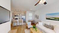 Located at 400 Claysburg Loop in Bloomingdale, Georgia, this two-story home offers a thoughtfully designed layout across two floors. The main level features a bright, open-concept kitchen and living area bathed in natural light. The kitchen is well-appointed with gray shaker-style cabinetry, a white quartz island with seating, stainless steel appliances including a gas range and French door refrigerator, a subway tile backsplash, and elegant pendant lighting. Light hardwood flooring flows throughout, complementing the home's clean, coastal aesthetic. The inviting living room features a ceiling fan, large windows with blinds, and a welcoming, airy atmosphere. A dedicated office on the upper level offers two windows with neighborhood views, making it an ideal workspace. The two bedrooms are comfortably sized, with the primary bedroom featuring a wall-mounted TV and ceiling fan. Three full bathrooms, including one with a tiled shower enclosure, provide ample convenience. A closet adds practical storage. Outside, a private fenced backyard with a covered patio area and string lights offers a pleasant outdoor retreat, ideal for relaxing or entertaining. The home combines modern finishes with a light, coastal charm throughout.