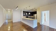 This well-appointed 2-bedroom, 2-bathroom single-floor residence offers a thoughtfully designed layout with modern finishes and an open, airy feel. The heart of the home is the open-concept kitchen and living area, where rich hardwood flooring flows seamlessly throughout the space. The kitchen is outfitted with dark espresso cabinetry, granite countertops, and a peninsula island complete with an undermount sink — ideal for both meal preparation and casual dining. Stainless steel appliances, including a refrigerator and range, complement the contemporary aesthetic, while a classic tile backsplash adds texture and visual interest. Pendant lighting hangs gracefully above the peninsula, complemented by track lighting that illuminates the entire kitchen and adjacent living area. Crown molding frames the ceilings, adding an elegant architectural touch. The open living space offers generous room for comfortable furnishings and benefits from natural light. With two full bathrooms and two bedrooms, this residence provides ample space for everyday living. The clean, neutral color palette throughout creates a versatile backdrop, making this a move-in-ready home that balances style and functionality.