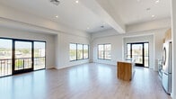 Located at 2001 Fifth Ave in Troy, NY, this contemporary residence offers a thoughtfully designed single-floor layout with three bedrooms and four bathrooms. The open-concept living and kitchen area immediately impresses with its expansive feel, accentuated by soaring ceilings with architectural beam detailing and an abundance of natural light streaming through large black-framed windows. Light wood-tone flooring flows seamlessly throughout, reinforcing the home's clean, modern aesthetic.

The kitchen is a standout, featuring warm wood cabinetry, a white tile backsplash, stainless steel appliances, and a generous island with a white countertop and undermount sink — ideal for both cooking and entertaining. The living area extends to a private balcony accessed via full-height glass sliding doors, offering sweeping views of the waterway and surrounding Troy cityscape.

The primary bedroom is a spacious retreat with vaulted ceilings, a ceiling fan, a walk-in closet, and a dedicated en-suite bathroom complete with a frameless glass walk-in shower. Additional bedrooms are bright and well-proportioned with light-filled interiors. The four bathrooms are finished in a clean, minimalist style with contemporary fixtures throughout, making this a polished and functional modern residence.