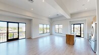 Located at 2001 Fifth Ave in Troy, NY, this contemporary residence offers a thoughtfully designed single-floor layout with three bedrooms and four bathrooms. The open-concept living and kitchen area immediately impresses with its expansive feel, accentuated by soaring ceilings with architectural beam detailing and an abundance of natural light streaming through large black-framed windows. Light wood-tone flooring flows seamlessly throughout, reinforcing the home's clean, modern aesthetic.

The kitchen is a standout, featuring warm wood cabinetry, a white tile backsplash, stainless steel appliances, and a generous island with a white countertop and undermount sink — ideal for both cooking and entertaining. The living area extends to a private balcony accessed via full-height glass sliding doors, offering sweeping views of the waterway and surrounding Troy cityscape.

The primary bedroom is a spacious retreat with vaulted ceilings, a ceiling fan, a walk-in closet, and a dedicated en-suite bathroom complete with a frameless glass walk-in shower. Additional bedrooms are bright and well-proportioned with light-filled interiors. The four bathrooms are finished in a clean, minimalist style with contemporary fixtures throughout, making this a polished and functional modern residence.