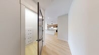 This thoughtfully designed one-bedroom, one-bathroom residence in Billerica, MA offers a clean, modern aesthetic throughout its well-appointed single floor. Light hardwood flooring flows seamlessly across every room, creating a bright and cohesive interior. The entry hallway, accessed through a striking dark-framed door, leads directly into the open-concept kitchen and living area. The kitchen is a standout feature, showcasing a large central island with a dark quartz countertop, crisp white lower cabinetry contrasted by warm wood-toned upper cabinets, a white subway tile backsplash, stainless steel appliances, and stylish pendant lighting. The living area is outfitted with a wall-mounted mini-split HVAC unit and charming double panel doors. The generously sized primary bedroom is filled with natural light from multiple windows and a sliding glass door that opens to an outdoor area with neighborhood views. The bathroom continues the design language of the home with a wood-grain vanity, dark quartz countertop, a framed mirror, tile flooring, and a tiled walk-in shower. Throughout the space, gray panel interior doors and black hardware accents lend a refined, contemporary character.