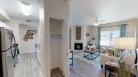 Located at 7901 N Cortaro Rd in Marana, Arizona, this single-story residence offers a well-designed layout with a cohesive, light-filled aesthetic throughout. The living room serves as the heart of the home, featuring a corner fireplace with tile surround, a ceiling fan, wood-style plank flooring, and a large window that invites natural light and outdoor views. Adjacent to the living area, the dining space benefits from a sliding glass door leading to a private patio, providing seamless indoor-outdoor connectivity. The kitchen is equipped with stainless steel appliances, including a range and over-the-range microwave, paired with white cabinetry, dark countertops, and the same wood-style flooring that flows throughout the main areas. A convenient entry closet adds practical storage near the main living space. The bedroom is a comfortable retreat, complete with plush carpeting, a ceiling fan, mirrored sliding closet doors, and its own sliding glass door opening to the patio. The bathroom features white cabinetry, a dark countertop vanity, and a shower-tub combination. Throughout the home, neutral wall tones and consistent finishes create a cohesive and inviting atmosphere well-suited to the Sonoran Desert setting.