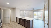 Located at 4781 Transit Rd in Depew, NY, this well-appointed 2-bedroom, 2-bathroom single-floor residence offers a thoughtfully designed layout with modern finishes throughout. The open-concept kitchen and living/dining area serves as the heart of the home, showcasing a large center island with a white quartz countertop, undermount sink, and pendant lighting overhead. Dark espresso cabinetry contrasts beautifully with the light countertops, while stainless steel appliances — including a range, built-in microwave, and dishwasher — complete the kitchen. Light-toned luxury vinyl plank flooring flows seamlessly throughout the entire unit, complementing the neutral color palette. The living area is bright and airy, with access to an outdoor balcony that brings in natural light. The spacious primary bedroom features multiple windows that flood the room with daylight, along with a generously sized walk-in closet equipped with wire shelving systems. The two bathrooms are finished with dark vanity cabinetry, light countertops, and wood-look flooring. A dedicated in-unit laundry room houses a full-sized washer with overhead wire shelving for additional storage. Five total closets provide ample storage throughout the residence.