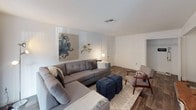 This single-story residence offers a well-organized layout across several distinct living spaces. The living room serves as the central gathering area, featuring wood-style flooring, a large sliding glass door that invites natural light and provides outdoor access, and ample room for generous seating arrangements.

The kitchen is equipped with white cabinetry offering substantial storage, granite-style countertops, a stainless steel sink, and black appliances including an electric range with overhead ventilation. The consistent countertop material connects the kitchen visually to the bathrooms throughout the unit.

The primary bedroom is a comfortable retreat with carpet flooring, a window dressed with sheer curtains for soft natural light, and enough space for a full furniture arrangement. A second bedroom mirrors this layout and offers similarly sized proportions with natural light from a window.

Both bathrooms feature the same granite-style vanity countertops, white cabinetry, wood-style flooring, and a tub-shower combination with tile surrounds and curved curtain rods. The cohesive finishes throughout create a unified aesthetic across the entire residence.