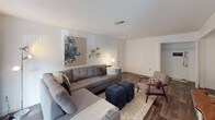 This single-story residence offers a well-organized layout across several distinct living spaces. The living room serves as the central gathering area, featuring wood-style flooring, a large sliding glass door that invites natural light and provides outdoor access, and ample room for generous seating arrangements.

The kitchen is equipped with white cabinetry offering substantial storage, granite-style countertops, a stainless steel sink, and black appliances including an electric range with overhead ventilation. The consistent countertop material connects the kitchen visually to the bathrooms throughout the unit.

The primary bedroom is a comfortable retreat with carpet flooring, a window dressed with sheer curtains for soft natural light, and enough space for a full furniture arrangement. A second bedroom mirrors this layout and offers similarly sized proportions with natural light from a window.

Both bathrooms feature the same granite-style vanity countertops, white cabinetry, wood-style flooring, and a tub-shower combination with tile surrounds and curved curtain rods. The cohesive finishes throughout create a unified aesthetic across the entire residence.