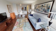 This single-floor residence offers a thoughtfully designed open-concept layout that seamlessly connects the living, dining, and kitchen areas. Rich hardwood flooring runs throughout the main living spaces, anchoring the open floor plan with warmth and continuity. The living room is generously proportioned, featuring large floor-to-ceiling windows that invite abundant natural light and frame outdoor views. A ceiling fan overhead and framed wall art add character to the space.

The dining area sits adjacent to the living room, accommodating a round table with modern chairs, and flows directly into the galley-style kitchen. The kitchen features dark cabinetry, granite-style countertops, a breakfast bar, and black appliances, including a full-size refrigerator.

The primary bedroom is spacious and well-lit, benefiting from corner windows that provide natural light and outdoor views. It connects to a bathroom featuring a solid-surface vanity and direct access to a walk-in closet with wire shelving. A second bedroom offers carpeted flooring and a built-in closet. A second bathroom includes a shower/tub combination, dark vanity cabinetry, and a solid-surface countertop. The overall ambiance is modern, bright, and cohesive.