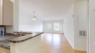 This 1-bedroom, 1-bathroom apartment at Bradlee Danvers in Danvers, MA spans 1,090 square feet of thoughtfully designed single-floor living space. Throughout the unit, warm-toned hardwood-style flooring and crisp white walls create a bright, clean aesthetic that maximizes the abundant natural light.

The open-concept kitchen and living room area is a central highlight, featuring a pendant light fixture, multiple windows with outdoor views, and direct access to a private balcony through a glass-paneled door. The kitchen is equipped with cream cabinetry, granite-style countertops, and black appliances including a refrigerator and range.

The primary bedroom measures 130 square feet and includes a window overlooking the exterior, providing natural light and outdoor views. A dedicated walk-in closet outfitted with wire shelving units and multiple hanging rods offers generous, organized storage.

The bathroom features earthy stone-look tile flooring, a white vanity with under-sink storage, a large mirror with overhead lighting, and a clean, functional layout. A dedicated closet room with hardwood-style flooring rounds out the unit, adding additional storage versatility. This well-appointed apartment combines comfort and practicality in a desirable Danvers location.
