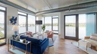 Located at 1900 Half St SW in Washington, DC's vibrant Southwest Waterfront neighborhood, this modern residence showcases an industrial-chic aesthetic defined by exposed silver ductwork, soaring ceilings, and warm hardwood flooring throughout. The expansive living area is the centerpiece of the unit, wrapped in floor-to-ceiling windows that frame breathtaking panoramic views of the Potomac River and the iconic Frederick Douglass Memorial Bridge, flooding the space with abundant natural light. The open-concept kitchen is outfitted with white cabinetry, dark stone countertops, a full suite of stainless steel appliances, and track lighting overhead. The bedrooms continue the industrial design language with exposed ductwork overhead and large windows — one offering sweeping waterfront views, another overlooking the dynamic surrounding cityscape — complemented by hardwood floors and generous closet access. Two well-appointed bathrooms feature white cabinetry with dark countertops, penny-tile flooring, and clean white tile work, with one offering a soaking tub and shower combination and the other a glass-enclosed walk-in shower. The overall ambiance is contemporary and sophisticated, blending urban energy with serene waterfront tranquility.