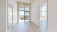 Located at 3918 Arizona St in San Diego's vibrant North Park neighborhood, this modern single-floor residence offers a thoughtfully designed layout with clean, contemporary finishes throughout. Light wood-style flooring flows seamlessly across the main living areas, complementing the crisp white walls and recessed lighting that lend the space a bright, airy feel.

The living area stands out with soaring ceilings and oversized sliding glass doors that open onto a private balcony, flooding the interior with abundant natural light and offering open views of the surrounding San Diego cityscape and tree-lined neighborhood. The balcony features a metal railing and provides a generous outdoor retreat with sunny southern California exposure.

The kitchen is outfitted with a modern two-tone design, featuring rich walnut lower cabinets paired with white upper cabinetry, light quartz countertops, a neutral subway tile backsplash, and a full suite of stainless steel appliances including a refrigerator, range, microwave, and dishwasher.

The bathroom is finished with clean white tile flooring, a combination tub and shower, and a walnut vanity with a white countertop and large mirror, echoing the kitchen's design language. Bedroom spaces include closet storage, and an in-unit washer and dryer area is also present. The overall ambiance is clean, modern, and move-in ready.