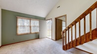 Located at 1835 Beacon Hill Cir in Cuyahoga Falls, Ohio, this single-floor residence offers a well-organized layout with notable architectural character. The living area immediately draws attention with soaring vaulted ceilings that lend an open, airy feel to the space. Soft carpeting covers the main living and bedroom areas, while tile flooring is found in the functional zones of the home. A staircase with warm wood railings adds visual interest and leads to an upper loft-style overlook, enhancing the sense of vertical space throughout.

The living room benefits from abundant natural light streaming through multiple windows with views of surrounding trees, and provides direct access to an outdoor deck, ideal for enjoying the wooded surroundings. The kitchen is equipped with warm oak cabinetry, ample upper and lower storage, a double sink, electric range, and a full-size refrigerator, all set on easy-care tile flooring with a textured ceiling above.

The bedroom features vaulted ceilings, a ceiling fan, soft carpeting, and a spacious walk-in closet with built-in shelving. The bathroom offers a full tub-shower combination and tile flooring. A dedicated laundry area accommodates a full-size washer and dryer alongside additional cabinetry, rounding out this practical and comfortable home.
