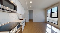 Located at 1669 Lincoln Ct in Santa Monica, CA, this single-level unit showcases a clean, contemporary design with consistent light wood-tone flooring and a neutral white color palette throughout. The kitchen is thoughtfully appointed with flat-front white cabinetry extending to the ceiling, a marble-look quartz countertop and matching backsplash, stainless steel Bosch appliances including a range, built-in microwave, and dishwasher, and a modern pull-down faucet over an undermount sink. Recessed lighting illuminates the space efficiently.

The living area is a standout feature, bathed in abundant natural light streaming through large, dark-framed floor-to-ceiling windows and a glass door that opens to an outdoor area, casting dramatic light patterns across the wood floors. The open layout creates a seamless flow between the kitchen and living spaces.

The bathroom is finished with marble-patterned tile flooring, a soaking tub with shower, a white vanity with quartz countertop, and a bright, clean aesthetic consistent with the rest of the unit. Overall, the space presents a modern, move-in ready environment with quality finishes throughout.