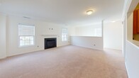 This single-story residence offers a practical and comfortable layout designed for everyday living. The open-concept living area is generously sized, finished with neutral wall-to-wall carpeting and crown molding, and anchored by a classic fireplace with a clean white mantel. Multiple windows allow natural light to fill the space from several angles, creating a bright and welcoming atmosphere.

The kitchen is positioned centrally and features a pass-through window that connects it to the main living area, promoting an open and connected feel. Warm-toned wood cabinetry provides ample storage, complemented by granite-look countertops and tile flooring. White appliances include a refrigerator, electric range, over-the-range microwave, and a sink with views into the living space. A dedicated laundry area with its own appliance connections is conveniently accessible nearby.

The bedrooms are carpeted and well-proportioned, each equipped with ceiling fans and windows fitted with horizontal blinds that allow adjustable natural light. The bathroom includes a full soaking tub with a clean white surround and chrome fixtures. Hallway access connects the bathroom to adjoining rooms, with additional door access providing flexible circulation throughout the home. The overall design prioritizes functionality with a neutral, move-in-ready aesthetic.
