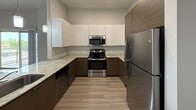 Located at 3001 E Apache Blvd in Tempe, AZ, this modern single-floor apartment offers 1,060 square feet of thoughtfully designed living space across three bedrooms and one bathroom. The open-concept kitchen and living area serves as the heart of the unit, featuring a U-shaped kitchen with two-tone cabinetry — white upper cabinets paired with warm wood-finish lower cabinets — granite countertops, a peninsula with an undermount sink, and a full suite of stainless steel appliances including a gas range, microwave, dishwasher, and refrigerator. Recessed lighting and a pendant light complete the kitchen. The spacious living room is finished with wood-style plank flooring, neutral gray walls, a ceiling fan, and sliding glass doors that open to a private balcony with outdoor views. The three bedrooms continue the consistent wood-style flooring and neutral palette; the primary bedroom measures 190 square feet and includes its own sliding door balcony access and a dedicated closet with built-in shelving and a hanging rod. The bathroom features a tiled walk-in shower with a sliding glass door and a vanity with dark cabinetry. Throughout the unit, clean lines and contemporary finishes create a cohesive, move-in-ready aesthetic.