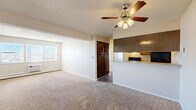 Located at 899 Westmoreland Rd in Colorado Springs, CO, this two-bedroom, one-bathroom unit offers a practical and comfortable single-floor layout. The open living room is carpeted and features a ceiling fan with integrated lighting and a textured ceiling, creating a cozy atmosphere. Natural light filters in through a window, and a baseboard heater ensures warmth year-round. The living space flows seamlessly into the kitchen via a half-wall pass-through, which is equipped with warm wood-toned cabinetry, a double stainless steel sink, laminate countertops, and black appliances including a range and refrigerator. Durable wood-look flooring runs throughout the kitchen, which also features a dedicated exterior door. Both bedrooms are carpeted and offer a comfortable sense of space. The primary bedroom includes a closet with double doors, while the second bedroom benefits from a bright window and baseboard heating. A hallway connects the main living areas to the shared bathroom, which features a wood-vanity with a light-toned countertop, a wide mirror, and warm overhead lighting. A dedicated closet provides additional storage.