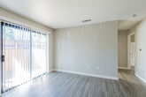 This single-floor residence offers a thoughtfully designed layout that balances functionality with comfort. The living area is bright and open, featuring light-toned luxury vinyl plank flooring, neutral beige walls, and a textured ceiling. A large sliding glass door dressed with vertical blinds floods the space with natural light and provides access to an outdoor area. A ceiling fan overhead adds to the room's practicality.

The kitchen is efficiently arranged in a U-shaped configuration, showcasing crisp white cabinetry with ample upper and lower storage, dark countertops, and a full suite of stainless steel appliances including a refrigerator, gas range, built-in microwave, and dishwasher. A pass-through opening connects the kitchen to the main living area, enhancing the sense of openness throughout the unit.

The bedroom is a serene retreat, finished with plush neutral carpeting and a window fitted with vertical blinds that allows for natural light while maintaining privacy. A mirrored closet door adds depth and practicality to the space.

The bathroom features a full tub-shower combination, a white vanity with dark countertop and a large mirror, and consistent vinyl plank flooring that ties the space together. Clean, neutral tones throughout the residence create a cohesive and move-in-ready atmosphere.