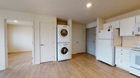 Located at 411 West Maple Street in Wichita, Kansas, this single-floor unit presents a clean, functional layout finished with consistent light wood-look flooring throughout every room, contributing to a bright and cohesive aesthetic.

The kitchen is well-appointed with white cabinetry offering ample storage, a full suite of white appliances including a refrigerator, electric range with over-the-range microwave, and a sink with countertop workspace. The layout provides an efficient flow suited for everyday use.

A dedicated laundry area houses a stacked washer and dryer unit, conveniently integrated into the living space alongside additional storage doors and direct access points within the unit.

The bedrooms are modestly sized with neutral walls and windows dressed with blinds and curtains, allowing natural light and outdoor views of the surrounding neighborhood. The rooms maintain a calm, understated atmosphere.

Two bathrooms serve the unit. One features a full tub and shower combination with a white vanity and drawers, while the other is a more compact space with a vanity, toilet, and towel rack. Both bathrooms continue the wood-look flooring found throughout the unit and are finished in neutral tones with brushed nickel hardware accents.