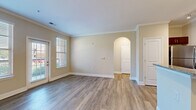 This well-appointed one-bedroom, one-bathroom unit in Murfreesboro, Tennessee offers a thoughtfully designed single-floor layout. The open-concept living and kitchen area serves as the heart of the home, featuring warm hardwood-style flooring, neutral-toned walls, and elegant crown molding throughout. A charming arched doorway adds architectural character to the living space, which is filled with natural light from multiple windows and a glass exterior door. The kitchen is a standout feature, boasting rich dark-wood cabinetry, granite countertops, a subway tile backsplash, and a full suite of stainless steel appliances including a range, microwave, refrigerator, and dishwasher. A peninsula with pendant lighting and an integrated sink provides additional prep space and casual dining potential. The bedroom offers plush carpeting, a ceiling fan, and dual windows that invite ample natural light. The bathroom mirrors the kitchen's design aesthetic with matching dark cabinetry, granite countertops, and wood-style flooring, complemented by a bright window. A dedicated closet and hallway complete this efficiently designed and move-in-ready home.