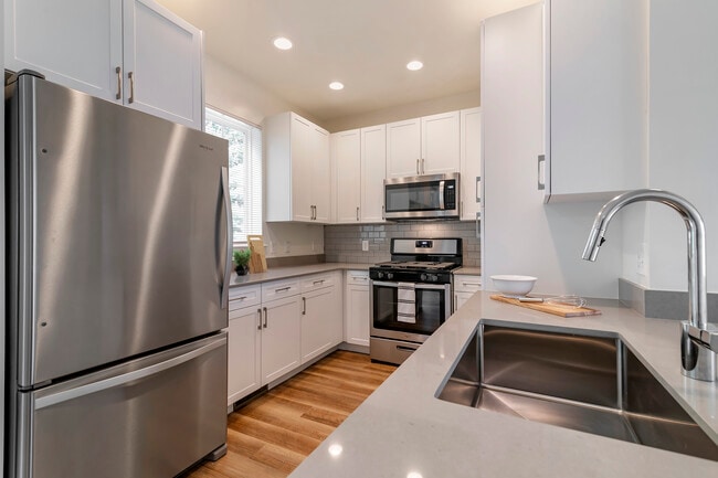 Renovated Package II kitchen with white cabinetry, grey quartz countertops,  grey subway tile backsplash, stainless steel appliances, and hard surface flooring - Avalon Northborough