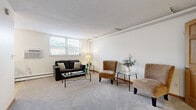 Located at 224 Smith Ave N in Saint Paul, Minnesota, this single-floor unit offers a well-organized layout comprising a living room, dining room, bathroom, and closet. The living room is the largest area of the unit, featuring neutral-toned carpet, cream-colored walls, and a textured ceiling. Two windows allow natural light to fill the space and offer views of the surrounding neighborhood, while a baseboard heating system and wall-mounted air conditioning unit provide year-round climate control. The open, uncluttered layout lends itself to flexible furniture arrangements. Adjacent to the living area, the dining room features light ceramic tile flooring, a window with blinds for natural light, and a baseboard heater — providing a cozy, functional space for meals. The kitchen area, visible in the floor plan, includes warm wood cabinetry and standard appliances, efficiently utilizing the available footprint. The bathroom is finished with neutral tile flooring and wall tiles, and includes a wood-framed vanity with a mirrored medicine cabinet, a toilet, and a shower/tub combination — all maintained in clean, functional condition. A dedicated closet adds practical storage. Overall, the unit delivers a straightforward, efficient living environment in a well-established Saint Paul neighborhood.