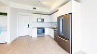 Located on the third floor of 215 Park in Hallandale Beach, Florida, this 1-bedroom, 1-bathroom unit showcases a clean, modern design with a bright and airy aesthetic throughout. Light wood-look flooring extends across the living areas and bedroom, lending warmth and continuity to the space.

The kitchen is thoughtfully designed with flat-front white cabinetry reaching toward the ceiling for ample storage, complemented by a marble-style backsplash and sleek gray countertops. A full suite of stainless steel GE appliances—including a French door refrigerator, dishwasher, range, and built-in microwave—provides both function and a polished look. Track lighting above highlights the kitchen's contemporary character.

The bedroom is bathed in natural light through a black-framed window offering outdoor views of greenery, and a ceiling fan ensures comfortable airflow year-round. White walls and clean baseboards maintain the unit's crisp, minimalist feel.

The bathroom features a tub-shower combination enclosed by sliding glass doors, with striking marble-veined wall tile adding an elevated, spa-like touch. Overall, the unit presents a well-finished, move-in-ready space with modern detailing throughout.