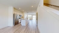 Located in Smyrna, TN, this well-appointed two-story home offers 2 bedrooms and 3 bathrooms across two thoughtfully designed floors. The main level features an open-concept kitchen and living area filled with natural light from large windows and a sliding glass door. The kitchen is a standout, showcasing white shaker cabinetry, stainless steel appliances, a granite-topped island with a matte black sink fixture, and recessed lighting throughout. Light wood-style flooring flows seamlessly from the kitchen through the living area, creating a bright and cohesive feel. A convenient half bath with a pedestal sink and matte black fixtures is also found on the main level. Upstairs, both bedrooms are carpeted and feature ceiling fans and windows with outdoor views of the surrounding neighborhood. The primary bedroom includes a walk-in closet with wire shelving. The upper-level bathrooms are finished with granite countertops, white cabinetry, and matte black hardware — one featuring a tub-shower combo with tile surround. Two closets provide ample storage throughout the home. Clean lines, neutral tones, and modern finishes give this home a fresh, move-in-ready appeal.