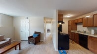Located at 9189 Gale Blvd in Thornton, Colorado, this single-floor residence offers a practical and well-organized layout designed for comfortable everyday living. The entry opens into a combined living and dining area finished with light wood-style flooring that extends throughout the main common spaces. The living room is bright and welcoming, featuring a large window that allows natural light to fill the room and provides views of the surrounding neighborhood. Baseboard heating units are present throughout, ensuring consistent warmth. The galley-style kitchen is efficiently arranged with warm wood cabinetry, granite-look countertops, and black appliances including an electric range, refrigerator, and dishwasher. A range hood and double-basin sink complete the kitchen's functional setup. A central hallway connects the main living spaces to the private areas of the home, which include multiple carpeted bedrooms. Each bedroom features windows fitted with vertical blinds and baseboard heating. The bathroom includes a tub and shower combination, a vanity with storage, and wood-style flooring. Throughout the residence, neutral wall tones and clean finishes create a cohesive, move-in-ready environment suited for a variety of lifestyles.