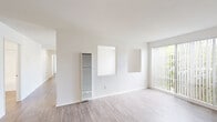 Located at 3301 Yorba Linda Blvd in Fullerton, CA, this single-floor, 2-bedroom, 2-bathroom residence offers a clean, modern aesthetic throughout. Wood-look plank flooring runs consistently across the entire unit, complementing the crisp white walls and creating a bright, cohesive feel.

The open living room is generously proportioned, bathed in natural light from a large sliding glass door fitted with vertical blinds. The door opens to a view of a community pool, adding a refreshing outdoor element. A wall-mounted air conditioning unit provides climate control, and a pass-through window connects the living area to the kitchen.

The kitchen features white cabinetry, a stainless steel sink, and includes a full-size refrigerator. The efficient layout makes practical use of the available space.

The primary bedroom is notably spacious and is served by a dedicated walk-in closet with wraparound shelving and hanging rods offering ample storage. The second bedroom includes a sliding panel closet. Both bedrooms continue the wood-look flooring and neutral white palette.

The two bathrooms are finished in white, each featuring a tub/shower combination. One bathroom includes a white vanity with a large mirror and bright overhead lighting. A hallway connects the various rooms, completing the functional and well-organized floor plan.