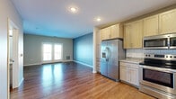 Located at 1331 Crossings Blvd in Shakopee, MN, this two-bedroom, one-bathroom residence offers a well-designed single-floor layout. The open-concept kitchen and living area serves as the heart of the home, featuring warm hardwood-style flooring, light-toned cabinetry, granite-look countertops, a white subway tile backsplash, and a full suite of stainless steel appliances including a French door refrigerator with ice maker, electric range, and built-in microwave. The living area is bathed in natural light and opens directly onto a private balcony through French doors, offering outdoor views of the surrounding area. The primary bedroom is a comfortable, well-proportioned space with plush carpeting and direct access to a spacious walk-in closet outfitted with wire shelving and hanging rods for ample storage. The second bedroom also features soft carpeting and neutral wall tones, providing a versatile space suitable for a guest room or home office. The bathroom includes a full soaking tub with a tiled surround and chrome fixtures. Throughout the unit, clean lines, neutral color palettes, and recessed lighting contribute to a bright and cohesive atmosphere.