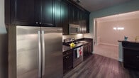 Located at 2139 Panoramic Way in Knoxville, Tennessee, this single-floor residence offers a thoughtfully designed layout with a cohesive blend of refined finishes and functional living spaces. The floor plan, visible in the 3D overview, reveals a well-organized arrangement of rooms connected by a clean, carpeted hallway.

The kitchen is a standout feature, showcasing floor-to-ceiling dark espresso cabinetry with under-cabinet lighting, dark granite countertops, and a suite of stainless steel appliances including a refrigerator, electric range, built-in microwave, and dishwasher. Rich hardwood-style flooring anchors the kitchen, and a peninsula with bar seating provides a casual dining option. Crown molding adds a polished architectural detail throughout.

The living area features a tray ceiling accented with crown molding and a ceiling fan, lending a sense of elevated space. Bedrooms are carpeted and bright, each equipped with ceiling fans and windows that draw in natural light and views of the surrounding greenery. The primary bedroom includes an en-suite bath and additional access to a separate room. The bathroom features granite countertops, white cabinetry, and tile flooring. Neutral tones throughout create a calm, welcoming ambiance.