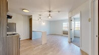 Located at 1151 E Main St in Meriden, Connecticut, this single-floor unit showcases a clean, modern renovation with carefully selected finishes throughout. The open-concept living and dining area is anchored by light-toned hardwood flooring and illuminated by elegant brass pendant lights with globe shades, creating a warm and inviting atmosphere. A white breakfast bar serves as a natural divider between the living space and the kitchen, adding both functionality and style.

The kitchen is efficiently designed with light wood cabinetry, a textured tile backsplash, white quartz countertops, a stainless steel refrigerator, and a gas range with oven. A range hood and under-cabinet storage complete this well-appointed cooking space.

The bedroom features plush carpeting and a bold charcoal accent wall that adds depth and character to the room. A globe pendant light fixture and a large window with grid detailing allow natural light to fill the space, offering pleasant outdoor views. A closet with panel doors provides ample storage.

The bathroom is elegantly finished with large-format dark marble-look floor tiles, a textured decorative wall treatment, and a floating vanity topped with a white basin. An LED-backlit mirror adds a contemporary touch, completing this refined and functional space.