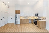This contemporary 620 square foot apartment in Bayonne offers a thoughtfully designed living space. The open concept layout maximizes the use of space, creating a sense of airiness and flow. Large windows flood the interior with natural light, while providing urban views.

The kitchen is a highlight, boasting a modern aesthetic with a combination of white upper cabinets and warm wood lower cabinets. Stainless steel appliances, including a French door refrigerator, complement the sleek design. A geometric tile backsplash adds visual interest.

The bedroom, measuring 140 square feet, features a sliding door closet with built-in organizers for efficient storage. Throughout the apartment, light wood-look flooring enhances the bright, fresh ambiance.

The bathroom continues the modern theme with a wood vanity, white countertop, and a shower/tub combination with sleek black fixtures. Recessed lighting throughout and exposed ductwork in the main living area add to the contemporary industrial feel.

This well-appointed apartment offers a perfect blend of style and functionality, ideal for urban living in Bayonne.