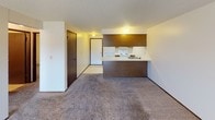 Located at 924 E Cozza Dr in Spokane, Washington, this single-floor unit offers a functional and straightforward layout across several well-defined spaces. The living area is generously sized, featuring neutral-toned carpet, a textured ceiling, and a baseboard heating system. A sliding glass door allows natural light to filter in and provides access to the outdoors. The kitchen is designed in a galley style, lined on both sides with warm wood-toned cabinetry offering ample storage. White appliances — including a refrigerator, electric range, and dishwasher — complement the light countertops and easy-care tile flooring. A peninsula counter connects the kitchen to the living area, creating an open, connected feel. The unit includes two carpeted bedrooms, each with a window fitted with blinds that bring in natural light while maintaining privacy. Both rooms feature baseboard heating and textured ceilings. The full bathroom is equipped with a single-sink vanity with wood cabinetry, a toilet, and a tub-shower combination with classic white tile accented by golden-hued tile details. Patterned vinyl flooring completes the bathroom. Overall, the unit presents a clean, practical living environment in a residential Spokane neighborhood.