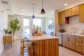 Located at 1350 S Bascom Ave in San Jose, California, this thoughtfully designed one-bedroom, two-bathroom residence offers a contemporary living experience across a single, efficiently organized floor. The open-concept layout connects the kitchen, dining, and living areas, creating a cohesive and airy atmosphere throughout.

The kitchen is a standout feature, showcasing warm wood-toned cabinetry, quartz countertops, a subway-tile backsplash, and a full suite of stainless steel appliances. A central island with pendant lighting above provides additional prep space and casual seating, making it both functional and stylish. Light wood-finish flooring runs throughout, reinforcing the modern, clean aesthetic.

The living room benefits from large floor-to-ceiling windows that flood the space with natural light and offer open outdoor views of the surrounding San Jose area. The bedroom is a calm, well-proportioned retreat featuring a built-in closet and a large window with sheer curtains that bring in abundant natural light.

Both bathrooms are finished with clean, neutral tile work. One bathroom features a floating wood vanity with a white countertop, while the second includes a full soaking tub with a tiled shower surround. The entrance and hallway provide a seamless transition throughout the unit. Overall, the space presents a polished, modern design with warm natural materials and bright, inviting interiors.