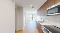 This contemporary 580 square foot apartment in Los Angeles offers a thoughtful blend of style and functionality. The space features two bedrooms, including a primary bedroom of 110 square feet, and one bathroom. The open-concept living area combines the kitchen and living room, maximizing the use of space.

Throughout the apartment, light wood flooring creates a warm, inviting atmosphere, complemented by crisp white walls that enhance the sense of spaciousness. Large windows in the bedrooms and living area flood the space with natural light and offer stunning views of the Los Angeles cityscape, including glimpses of distant skyscrapers.

The kitchen boasts modern amenities with sleek stainless steel appliances, including a built-in microwave and refrigerator. Wood-grain cabinetry adds a touch of warmth, while white countertops and a tiled backsplash maintain a clean, contemporary aesthetic.

Sliding glass doors in one of the rooms lead to a small balcony, perfect for enjoying the urban views. The bathroom, while not pictured, likely continues the modern design theme of the rest of the apartment.

Despite its compact size, the apartment's layout feels open and airy, with each room flowing seamlessly into the next. The use of mirrored closet doors in the bedrooms further amplifies the sense of space. This apartment offers a perfect blend of urban living and modern comfort in the heart of Los Angeles.
