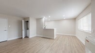 This thoughtfully updated single-floor unit offers a clean, contemporary aesthetic throughout. The open-concept living and dining area is finished with light-toned luxury vinyl plank flooring and neutral warm-beige walls, creating a bright and welcoming atmosphere. Recessed pot lighting illuminates the space evenly, while a half-wall peninsula serves as a natural divider between the living area and the rest of the unit. A dedicated laundry closet with stacked appliances is conveniently accessible from the main living space.

The kitchen is well-appointed with medium-toned wood laminate cabinetry, brushed hardware, a white subway tile backsplash, and white appliances including a refrigerator, gas range, built-in microwave, and dishwasher. The light plank flooring continues seamlessly into this space.

Both bedrooms feature soft, neutral carpet and windows with blinds that allow for natural light. The primary bedroom is notably generously sized and offers the added convenience of two separate closets with built-in shelving and rods.

The full bathroom includes large-format tile surround surrounding a soaking tub, a sleek white vanity, and an illuminated mirror. A separate powder room provides a white vanity, toilet, and framed mirror, ideal for guests.